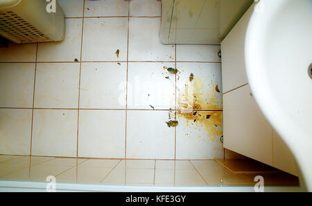 Colorful stains and broken glass on white bathroom tiles. Stock Photo