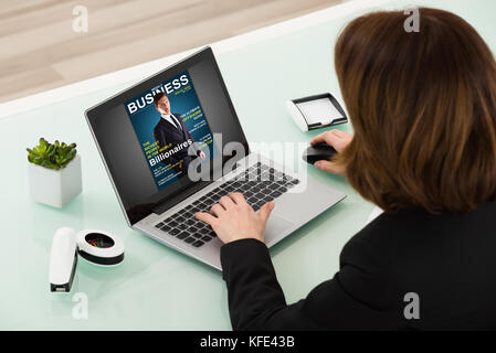 Close-up Of Businesswoman Reading Online Magazine On Laptop Stock Photo