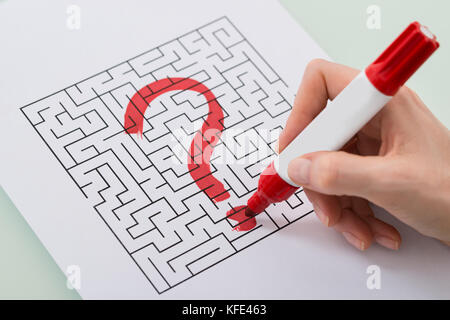 Close-up Of Woman Hand With Question Mark On Maze Over Paper Stock Photo