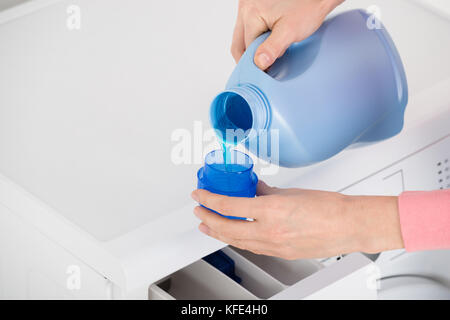 Closeup of liquid gel detergent pouring from the spout of a plastic bottle  into a measuring cup, with dirty washing / laundry in the background Stock  Photo - Alamy