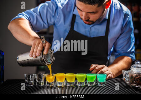 Barman is preparing Rainbow color shots Stock Photo