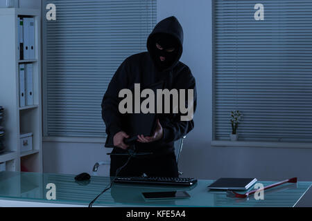 Thief Stealing Computer From Office At Night Stock Photo