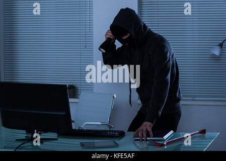 Robber Stealing Laptop With Flashlight In Hand Stock Photo