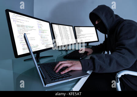 Hacker Stealing Data On Multiple Computers And Laptop Stock Photo