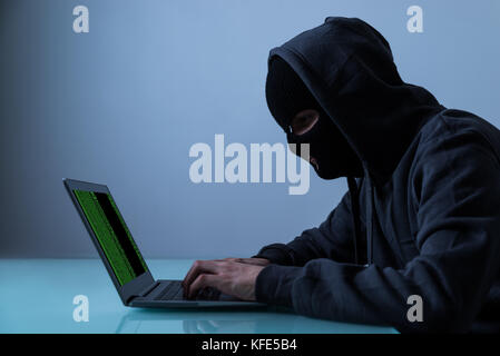 Hacker Stealing Information From Laptop In Office At Night Stock Photo