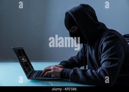 Hacker Stealing Information From Laptop In Office At Night Stock Photo