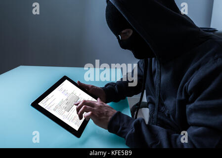 Hacker Stealing Information From Digital Tablet In Office At Night Stock Photo