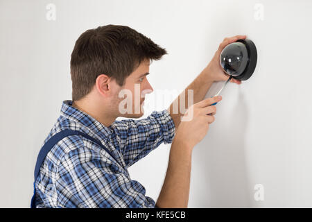 Young Male Technician Installing Surveillance Camera On Wall Stock Photo
