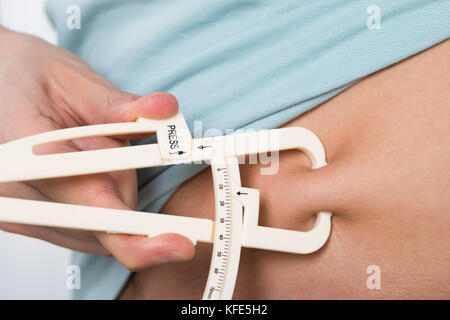 Close-up Of Man Measuring Stomach Fat With Caliper Stock Photo