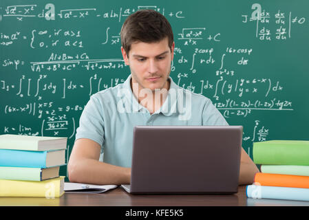 Young Man Using Laptop While Studying In Classroom Stock Photo