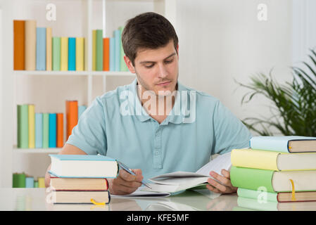 Photo Of Young Man Reading Book In Library Stock Photo