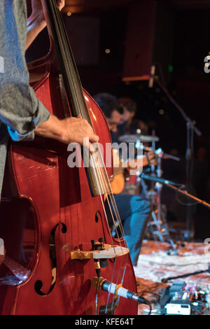 Acoustic trio band performing on a stage in a nightclub, with the double bass player in focus Stock Photo