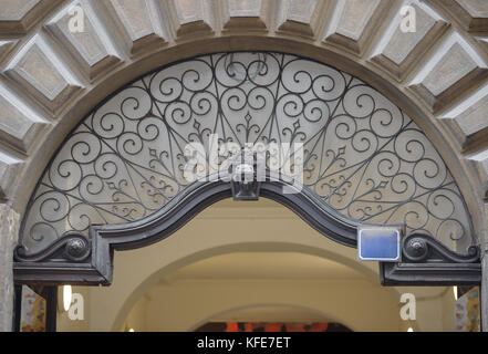 Close-up decorative glass and thin wrought pattern iron bars pediment in archway of old building on Zlatnicka Street in Prague Peter quarter, Czech Re Stock Photo