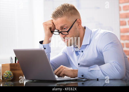 Contemplated Businessman Sitting With Laptop At Workplace Stock Photo