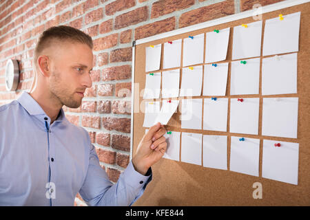 Close-up Of A Businessman Looking At Notes Attached On Bulletin Board Stock Photo