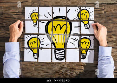 Businessman With Light Bulb Drawing On White Paper Over The Wooden Desk Stock Photo