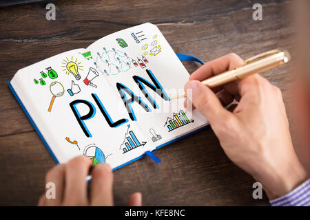 Businessperson Drawing The Plan Chart On Notebook With Pen Over The Wooden Desk Stock Photo