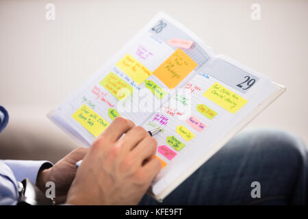 Close-up Of Man Writing Important Notes In Diary With Pen Stock Photo