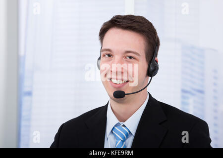 Portrait of confident young businessman wearing headset in office Stock Photo