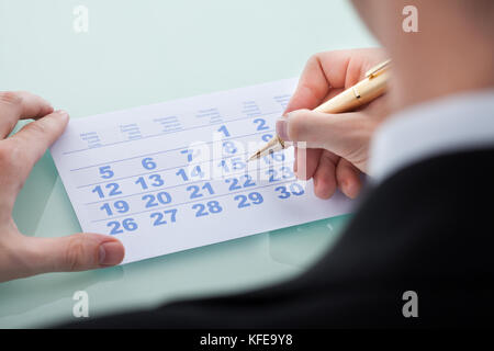 Closeup of man's hand marking date 15 on calendar Stock Photo