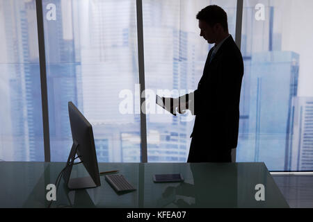 Side view of young businessman using digital tablet at desk in office Stock Photo