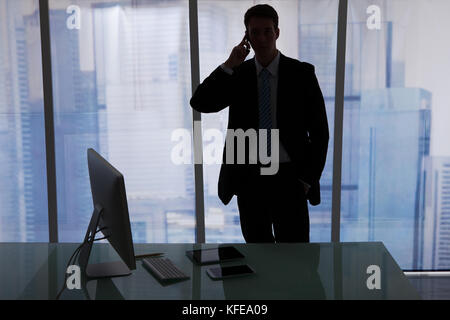 Young businessman using cell phone at office desk Stock Photo