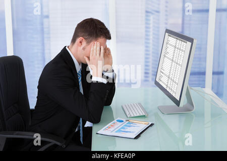 Young businessman suffering from headache at computer desk in office Stock Photo