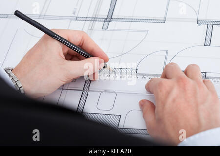 Cropped image of businessman working on blueprint at desk in office Stock Photo