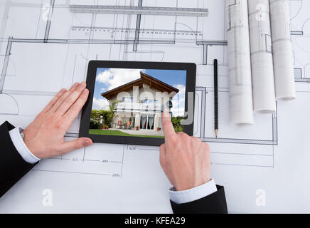 Cropped image of male architect using digital tablet on blueprint in office Stock Photo