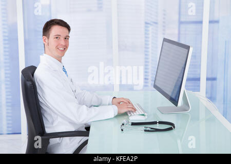 Portrait of young male doctor using computer at desk in clinic Stock Photo