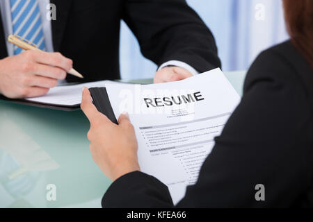 Cropped image of female candidate holding resume at desk during interview Stock Photo