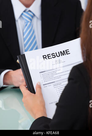 Cropped image of female candidate holding resume at desk during interview Stock Photo