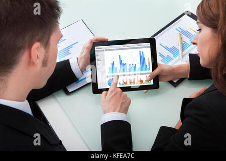 Young business people discussing over graphs on digital tablet at office desk Stock Photo