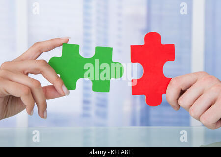 Cropped image of business people joining jigsaw pieces in office Stock Photo