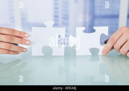 Cropped image of business people joining jigsaw pieces in office Stock Photo