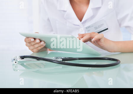 Midsection of female doctor using digital tablet in clinic Stock Photo