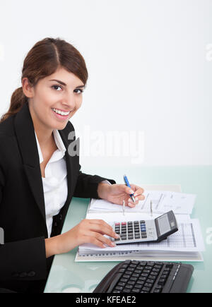 Cropped image of young businesswoman calculating bills at desk in office Stock Photo