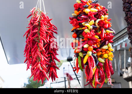 Hanging strings of mixed hot chili peppers for sale at Sineu market, Majorca, Spain Stock Photo