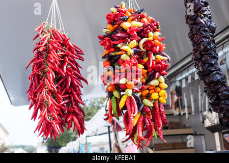 Hanging strands of mixed colourful chili peppers for sale at Sineu market, Majorca, Spain Stock Photo