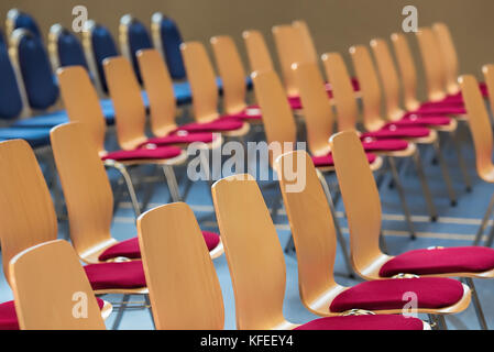 Blurred rows of empty wooden chairs in a large assembly hall.Empty chairs in conference hall.Interior meeting room.Nobody. Stock Photo