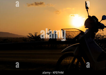 silhouette young photographed and rested on a mountain sunset. Stock Photo