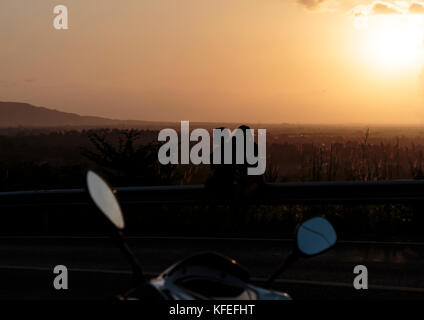 silhouette young photographed and rested on a mountain sunset. Stock Photo