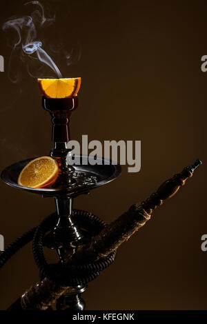 Smoking hookah with fruit head on dark background Stock Photo