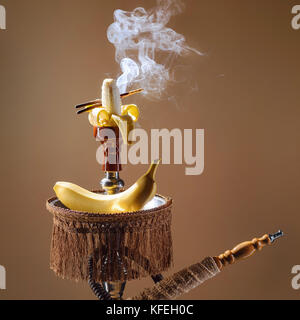 Smoking hookah with fruit head on dark background Stock Photo