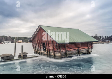 Beautiful red fishing shack and boat house surrounded by ice. Stock Photo