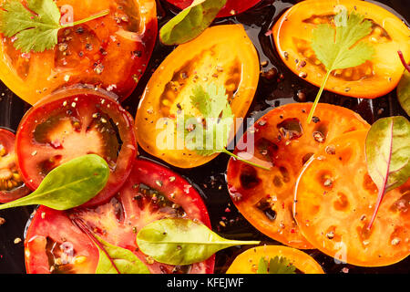 Sliced tomatoes with spices and oil on dark Stock Photo