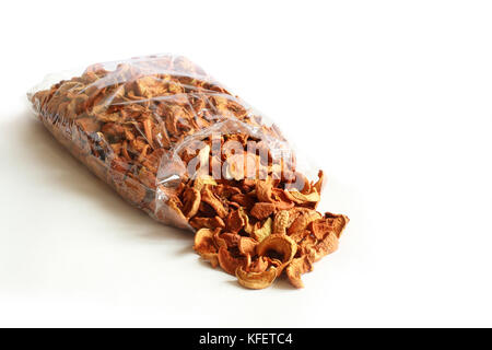 Dried pieces of apples poured out of a transparent package against white background Stock Photo