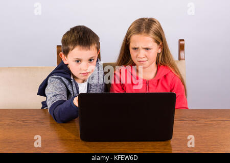 Boy shows something strange to his sister on a laptop Stock Photo