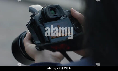 Photographer girl shooting images. woman hands holding camera taking photos. Girl looks at the camera screen. Stock Photo