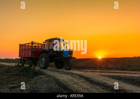 Farm tractor with a trailer on country road Stock Photo